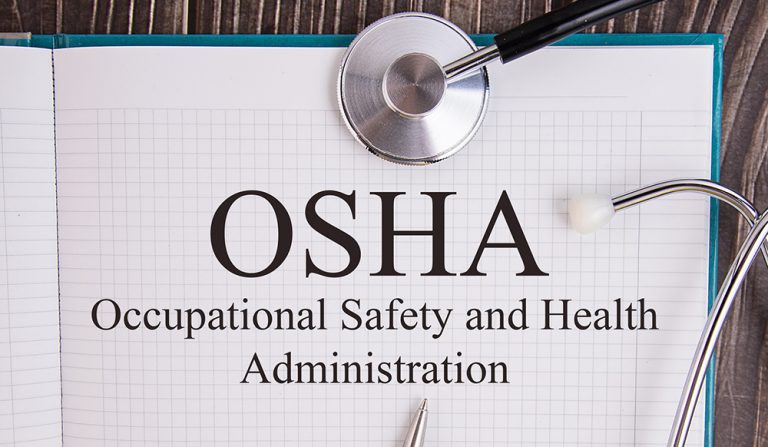 Notebook page with text OSHA Occupational Safety and Health Administration, on a table with a stethoscope and pen, medical concept.