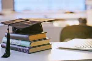 Graduation cap, books and laptop or university education for future goal, scholarship or online. Studying, research and thesis proposal for final school project for learning course, report or student